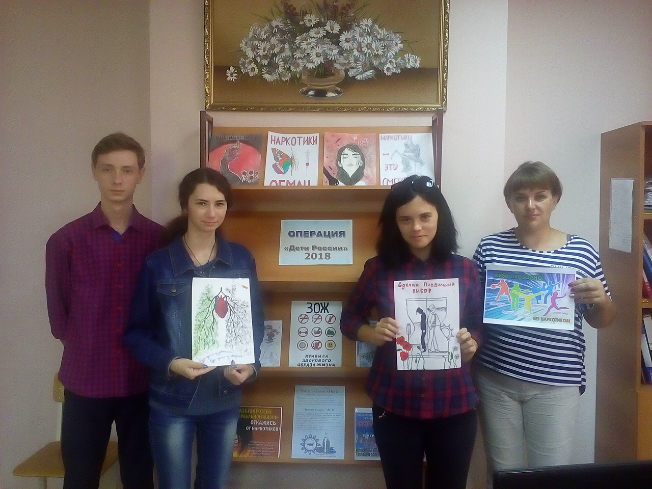 Студенты и педагог у выставки профилактических плакатов
